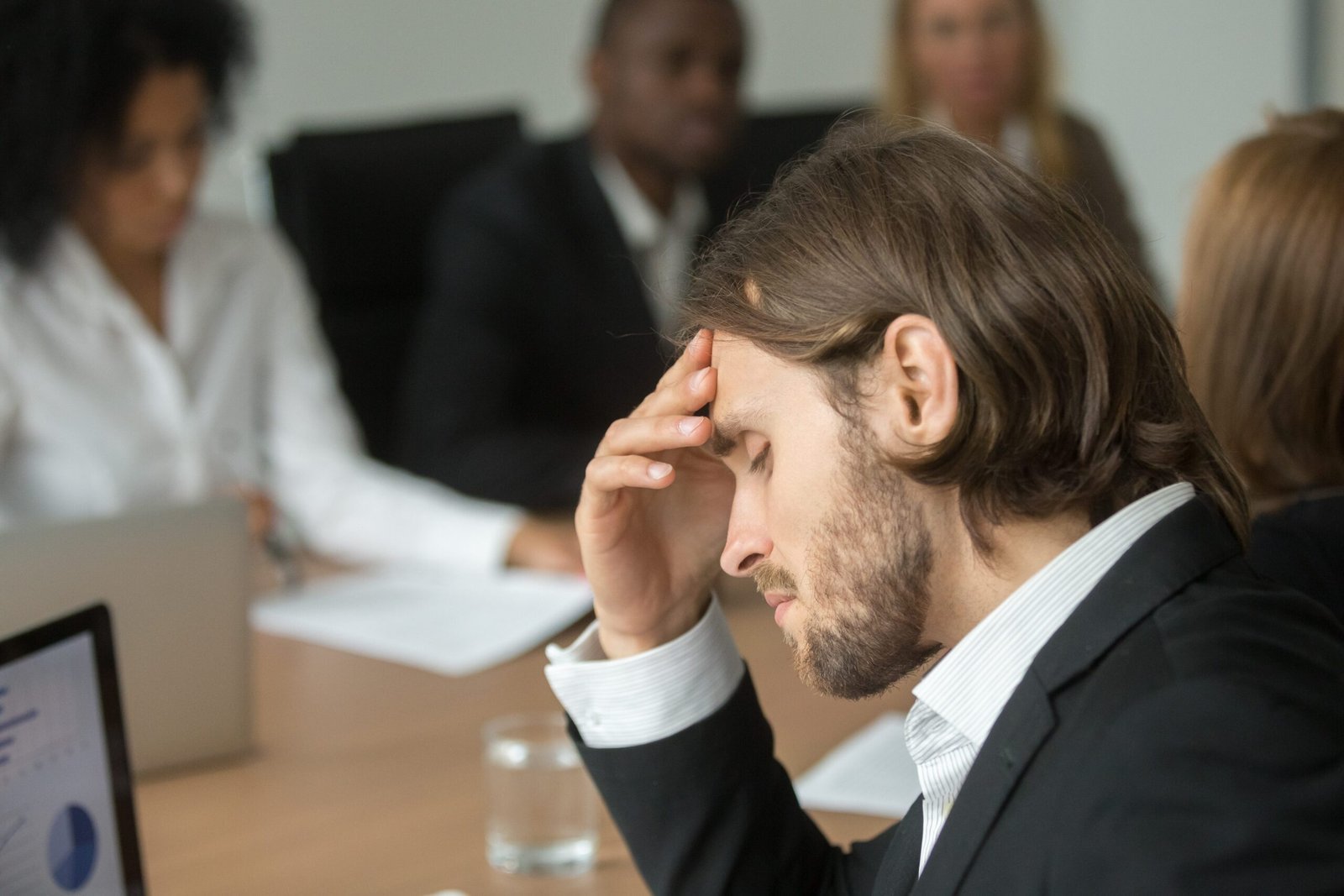 Frustrated tired businessman having strong headache at diverse t Feeling Overwhelmed as a Leader