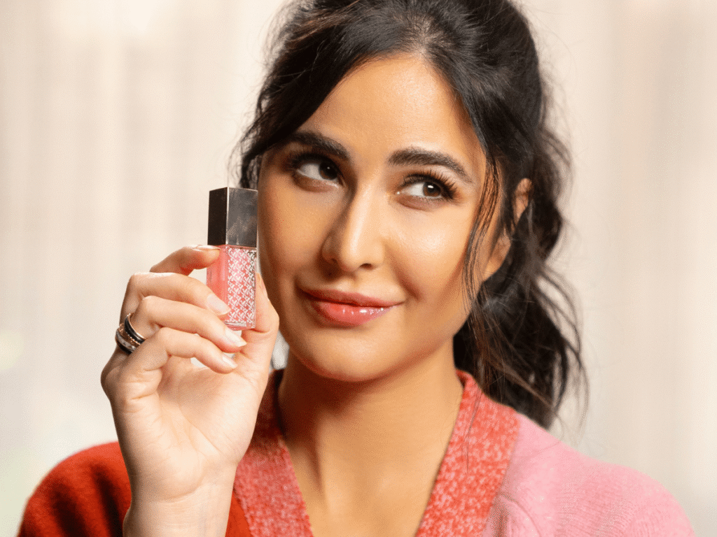 Woman holding a lip gloss product for a beauty promotion.